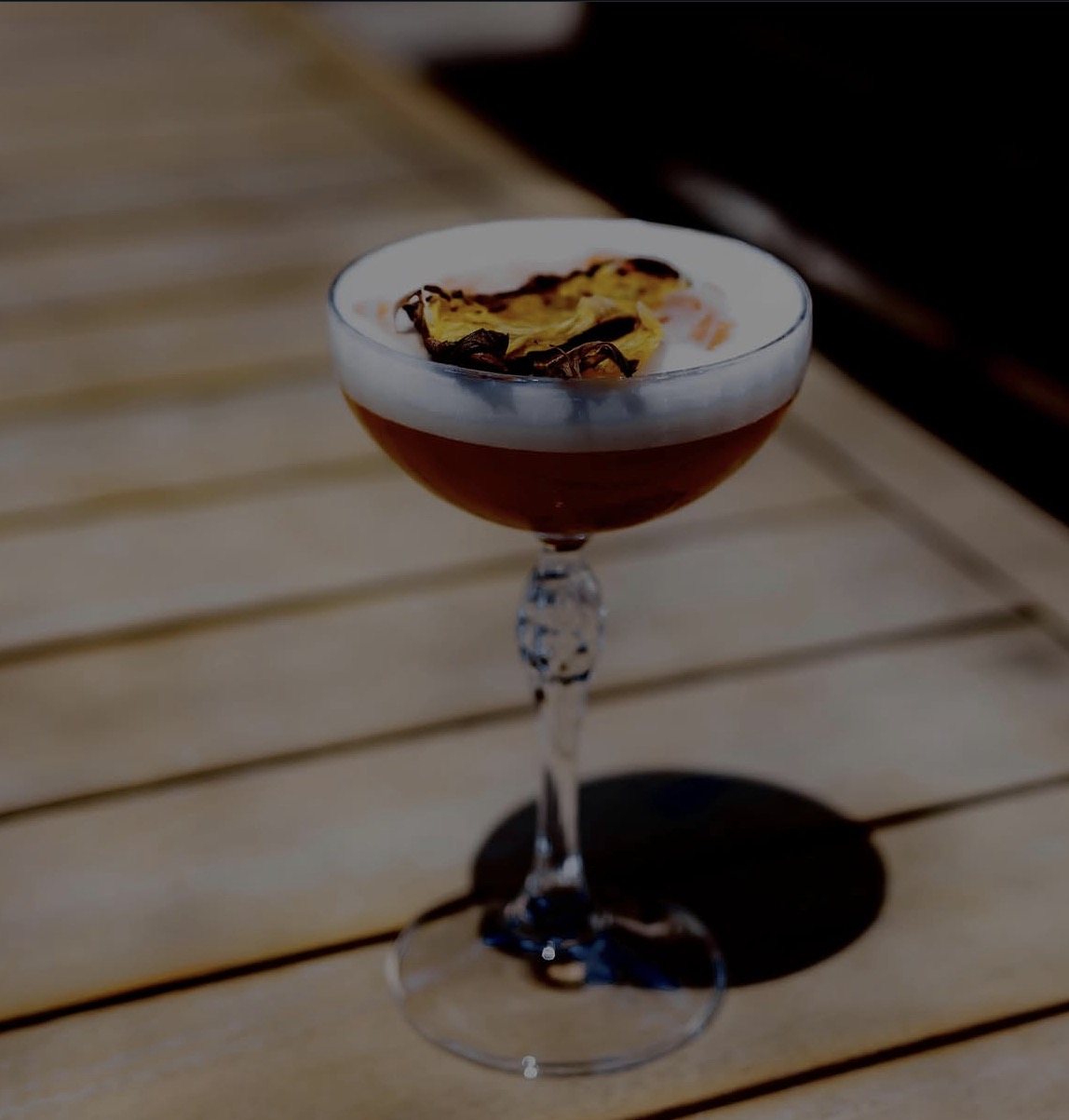Cocktail signature en coupe sur la table en bois de la terrasse