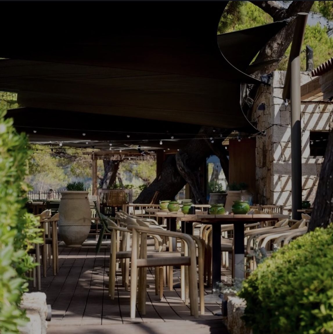 La terrasse sous les voiles d'ombrage et les guirlandes, jarres et poteries vertes
