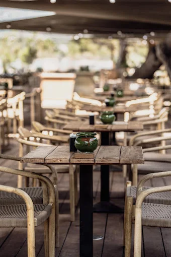 Tables en bois et fauteuils en rotin sur la terrasse d'A Piaghja